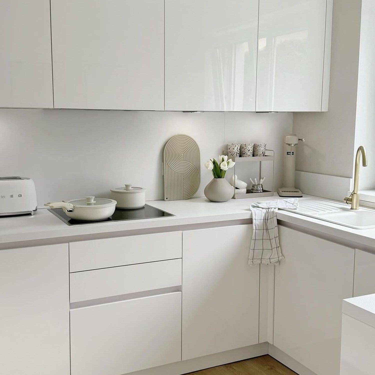 A modern minimalist kitchen with sleek white cabinetry and a neutral color palette