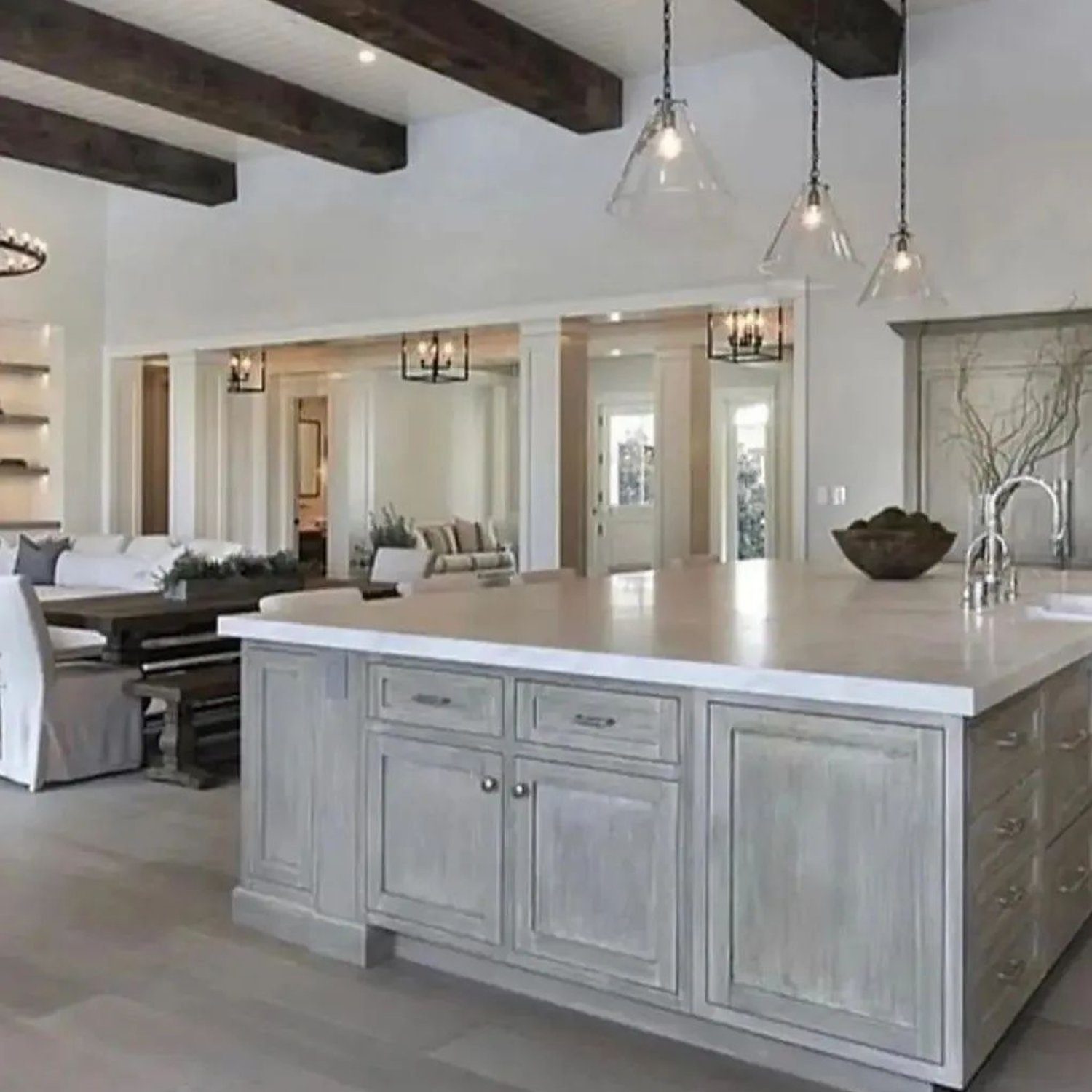 Elegant and spacious kitchen and living area with white walls, dark wooden beams, and large island