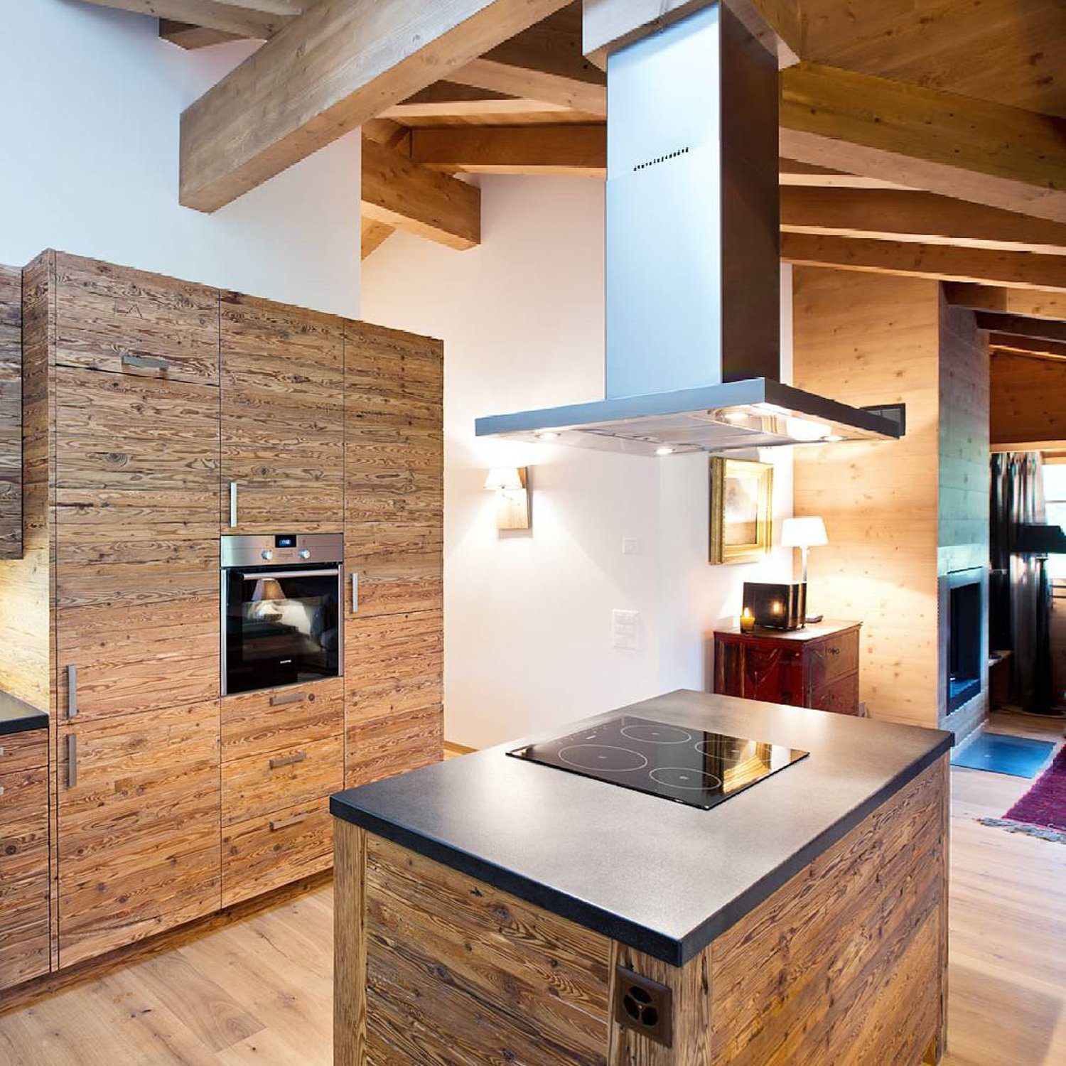 A modern rustic kitchen featuring reclaimed wood cabinetry and beams, with state-of-the-art appliances