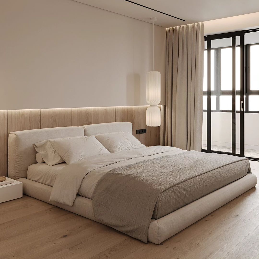 A contemporary bedroom with a plush beige upholstered bed, soft white bedding, matching wooden wall paneling and flooring, and minimalistic pendant lights providing a serene ambiance.