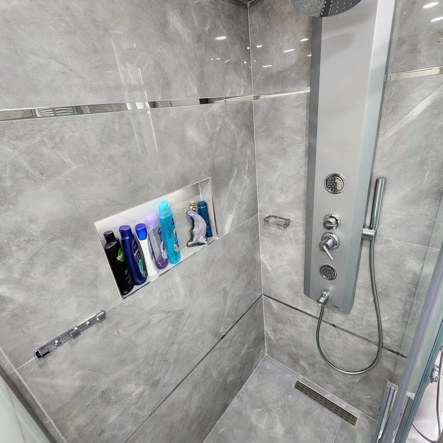 A modern, sleek shower with marble-look tiles and multiple shower heads