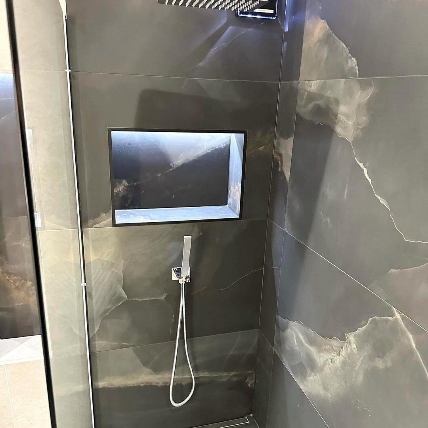 Luxurious grey tiled bathroom shower with a built-in screen