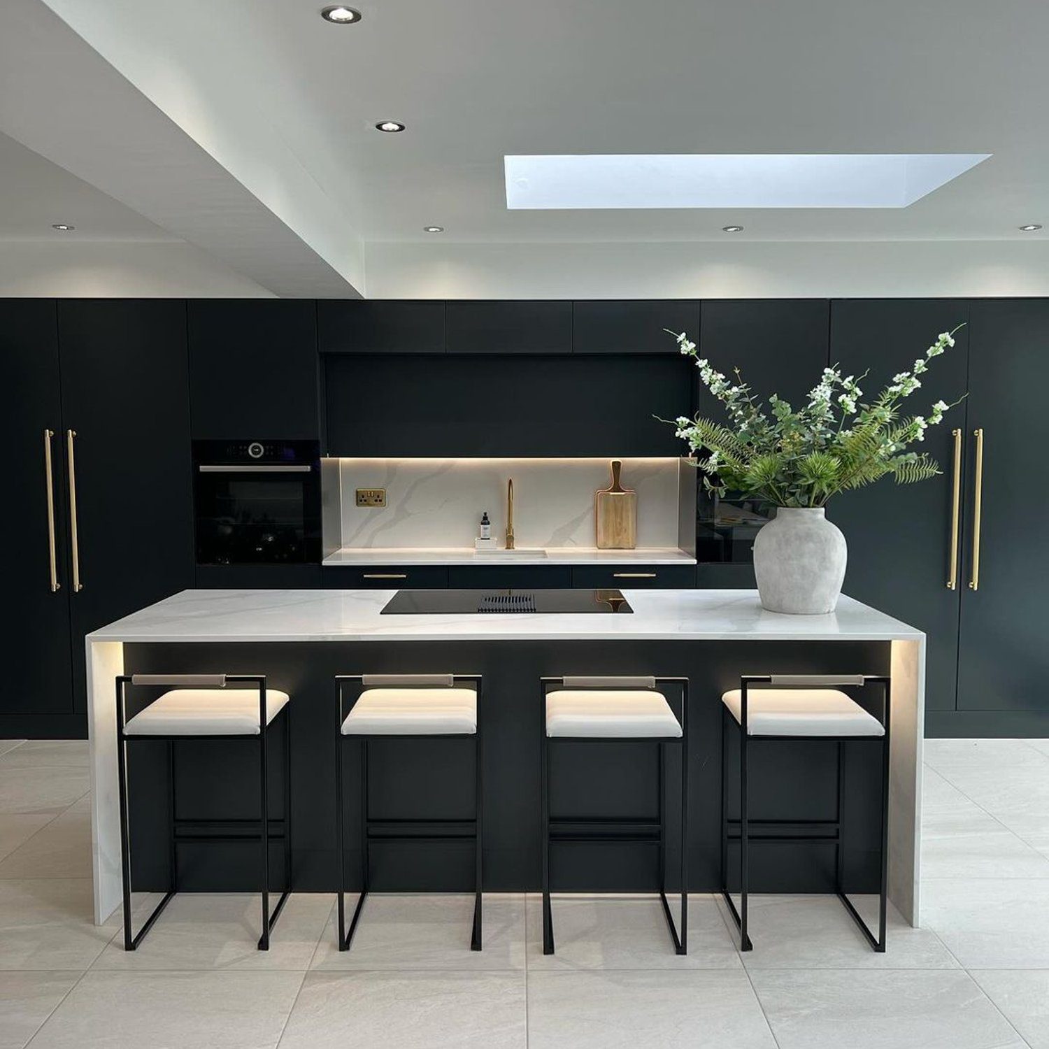 A modern kitchen with sleek black cabinetry and gold accents