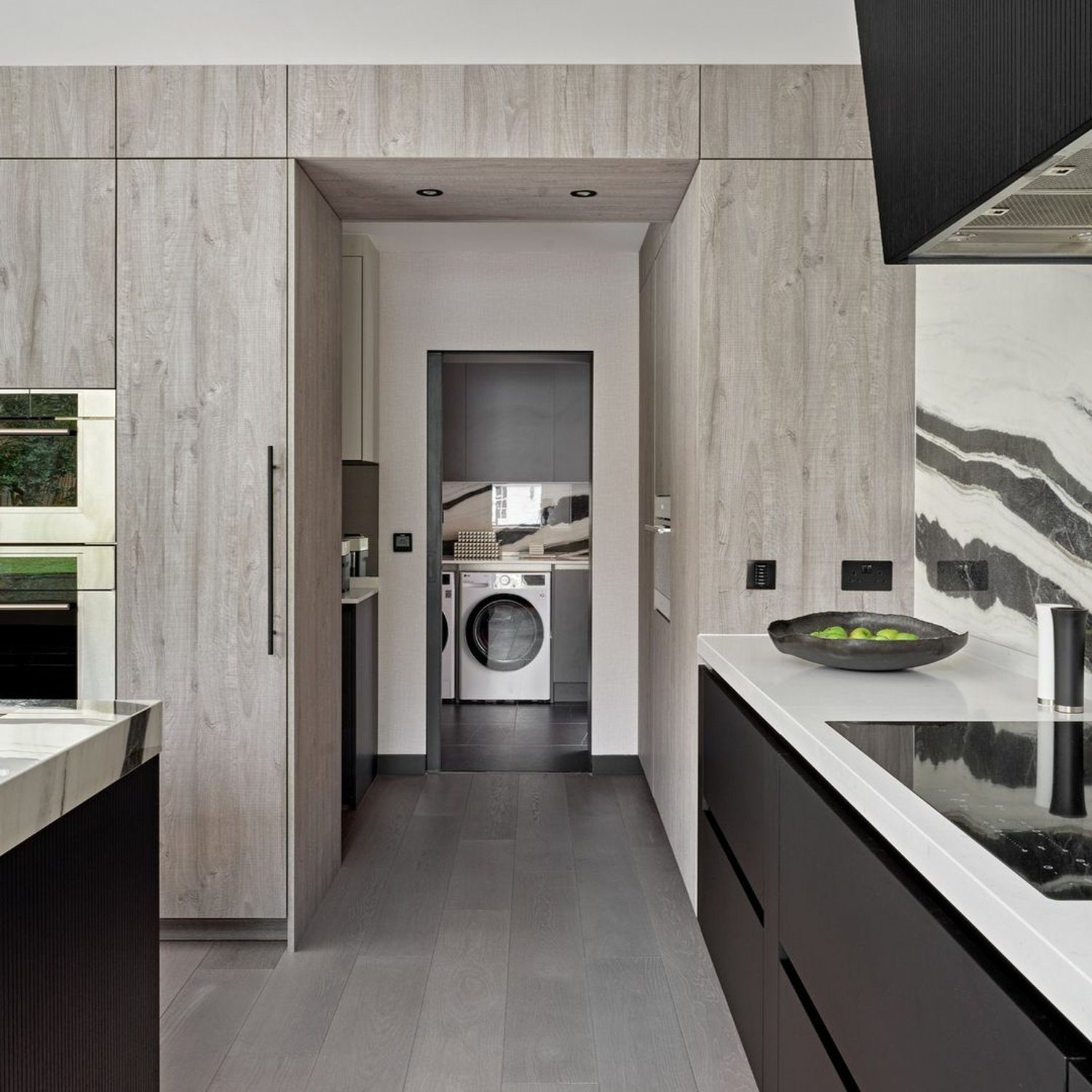 A modern and sleek kitchen design featuring light wood cabinetry and dark flooring