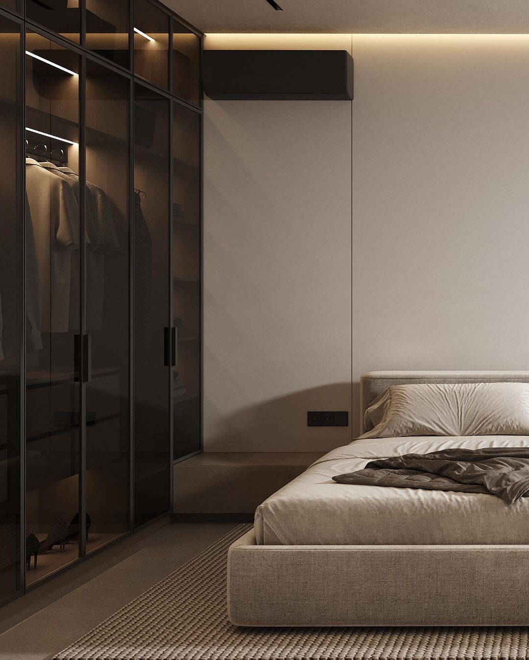 A modern and sophisticated bedroom featuring a large low bed with a textured fabric headboard, a woven area rug, and sleek wardrobe with glass doors