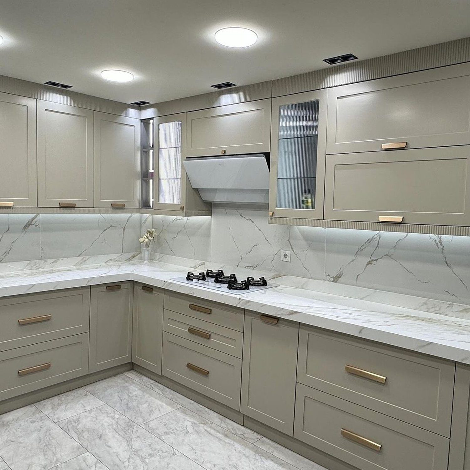 Elegantly designed modern kitchen featuring taupe cabinetry and marble countertops