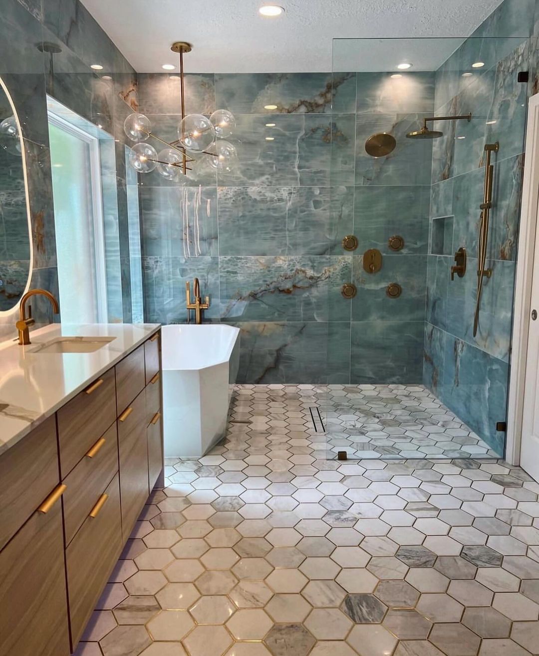 A luxurious bathroom featuring teal marble walls and gold fixtures