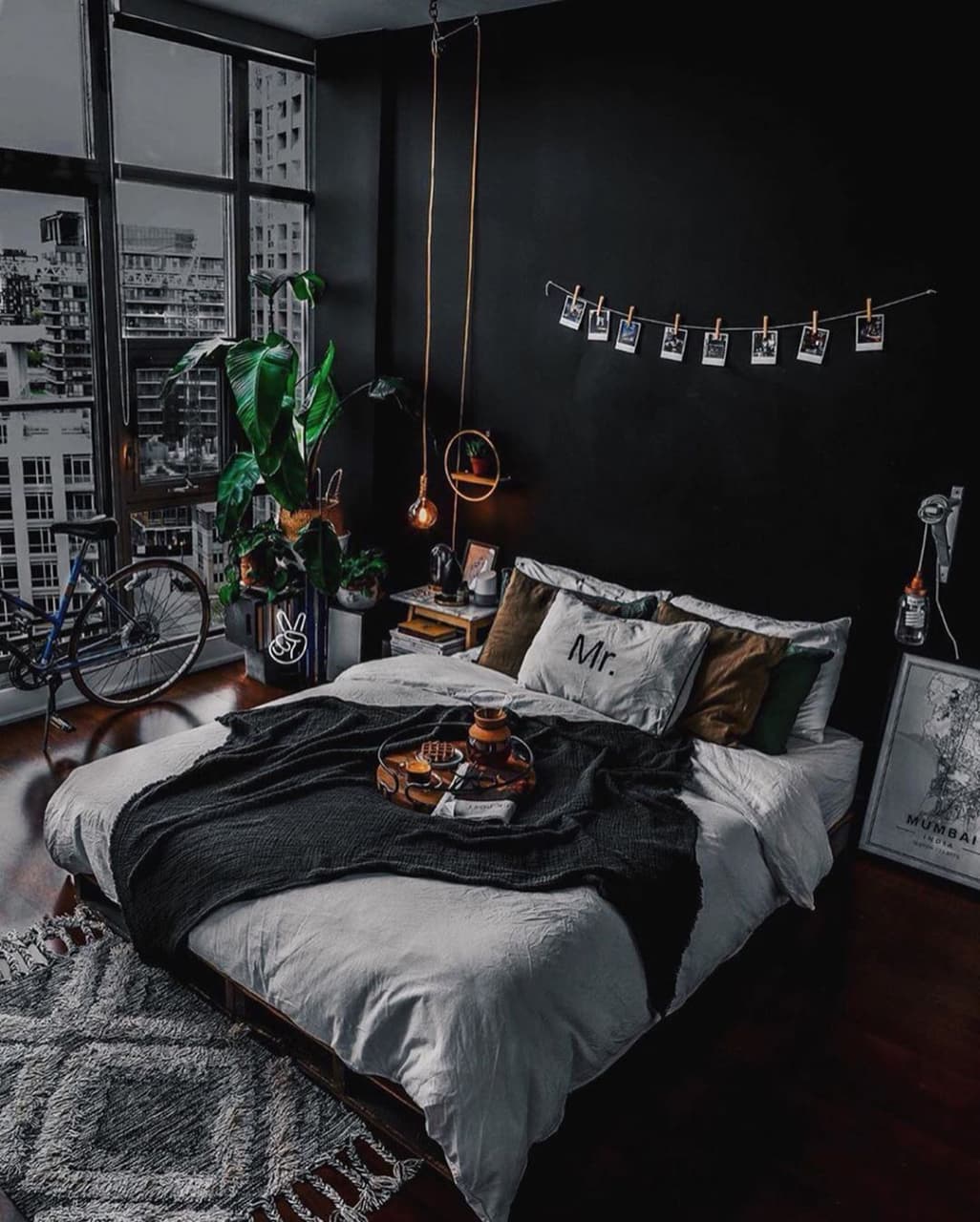 A modern urban bedroom highlighting deep contrasts with black walls and pops of greenery