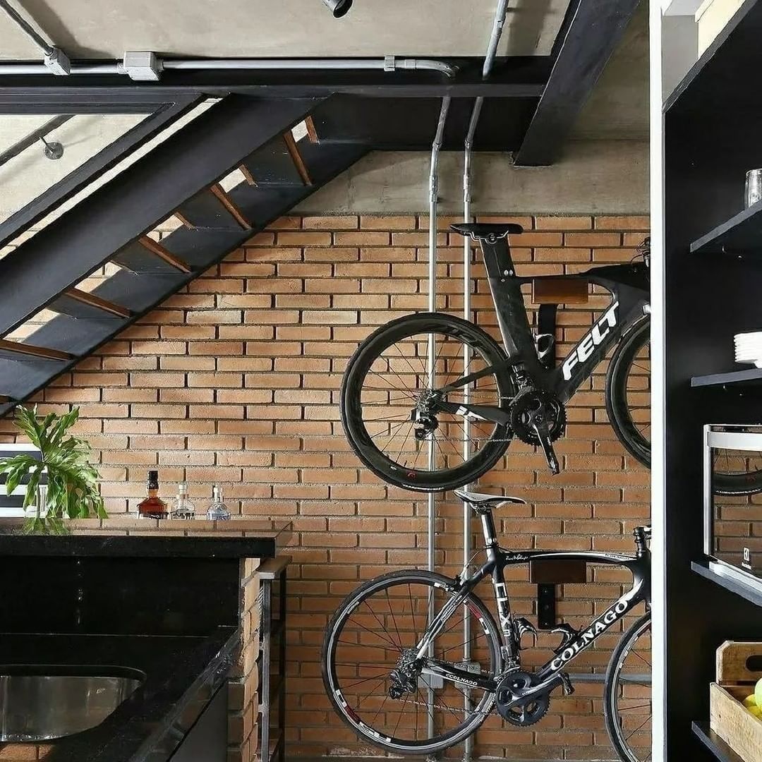 A modern-urban kitchen featuring exposed industrial elements and brick walls, with two road bicycles artistically mounted on the wall