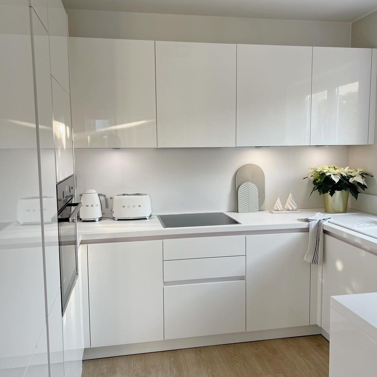 A sleek and modern all-white kitchen with minimalist cabinetry and contemporary appliances.