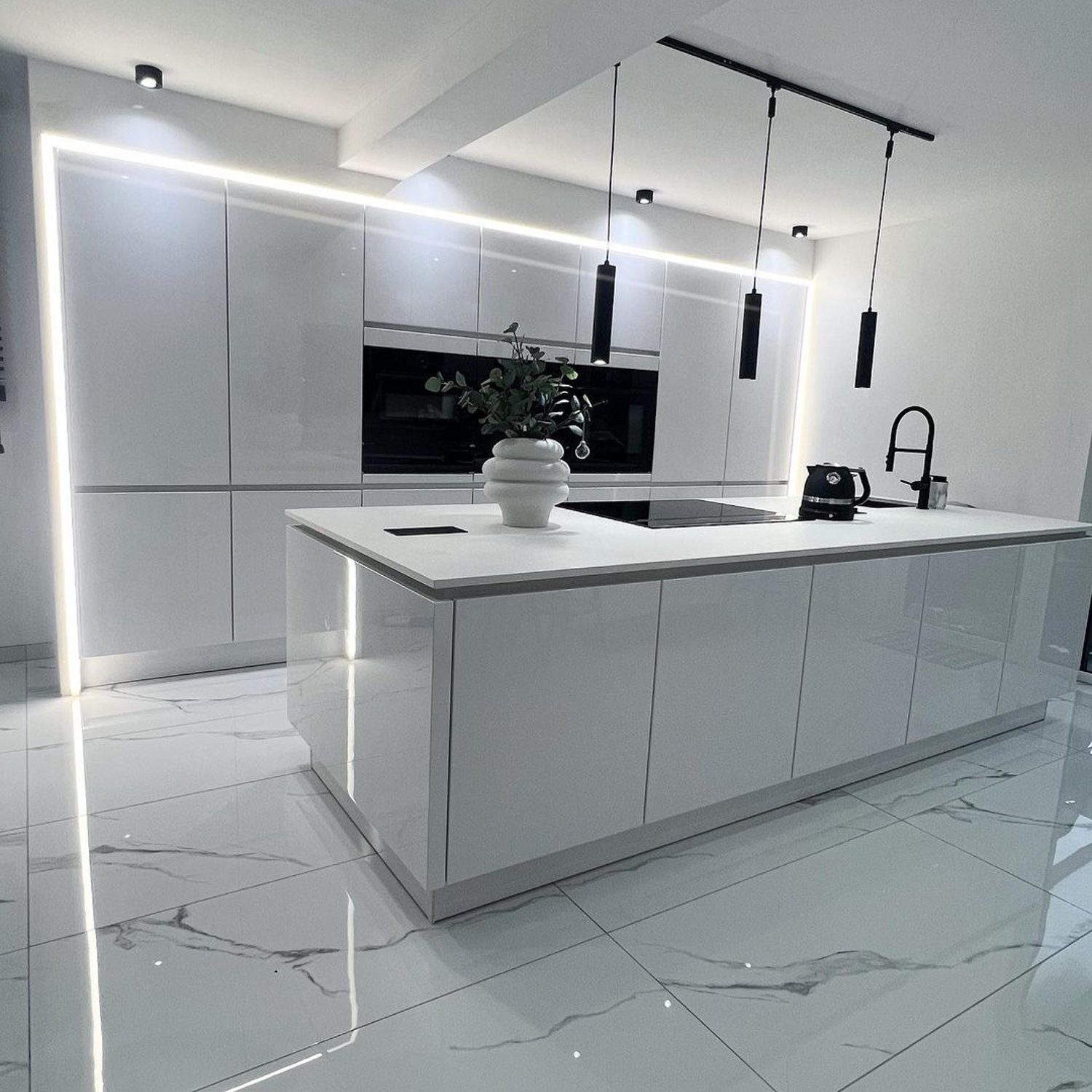 A sleek and modern kitchen featuring high-gloss white cabinetry, reflective marble flooring, and elegant pendant lighting