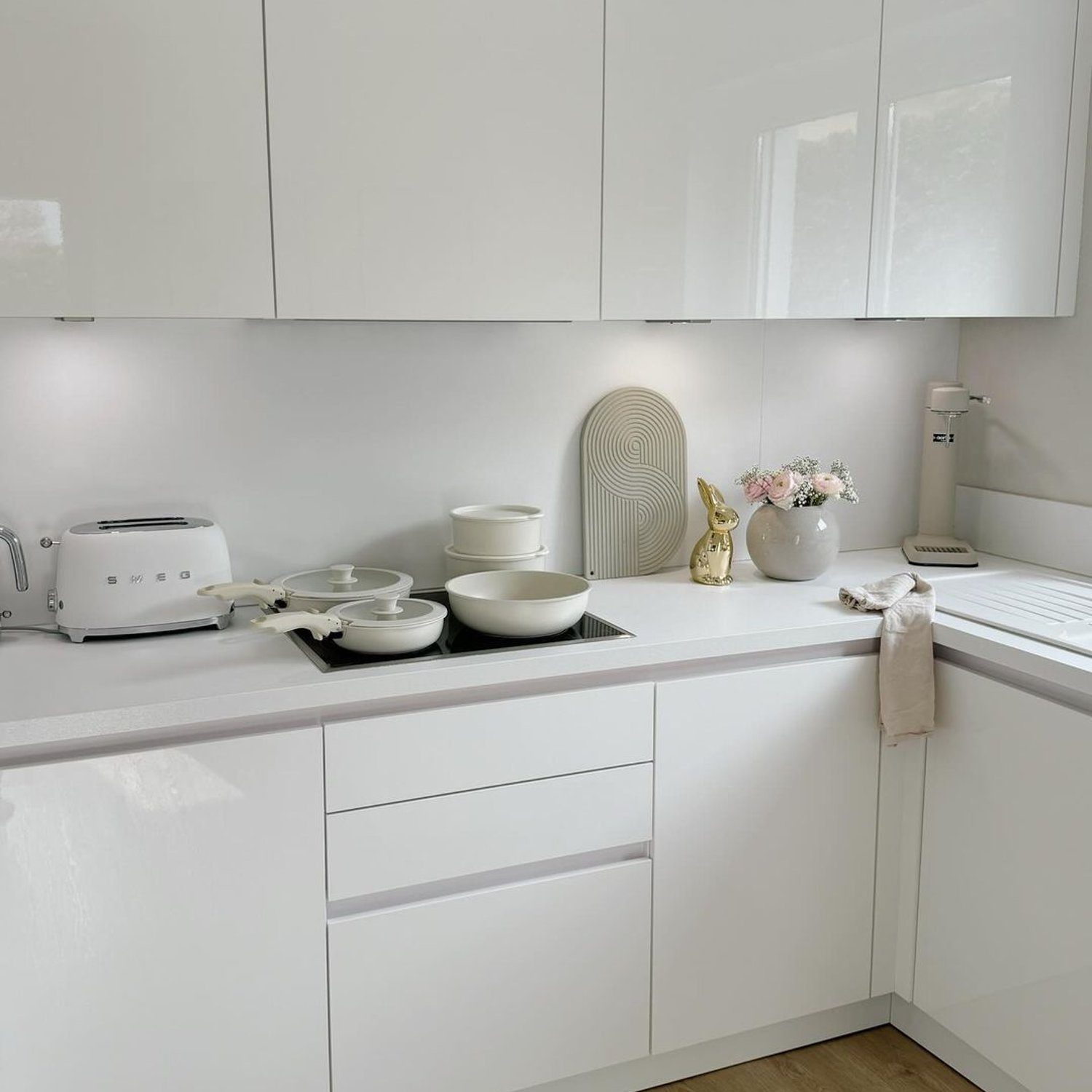 A sleek and minimalist white kitchen setting with modern appliances and decorative accents