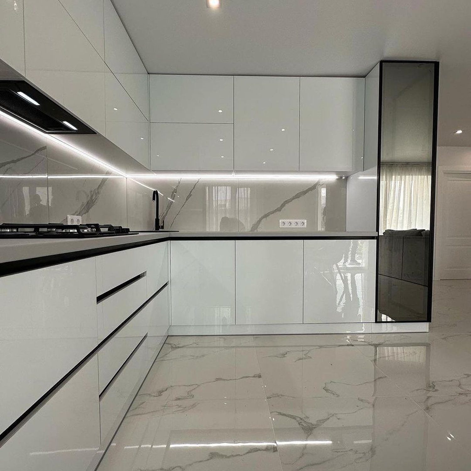 A sleek and modern kitchen featuring reflective white surfaces and marble floors