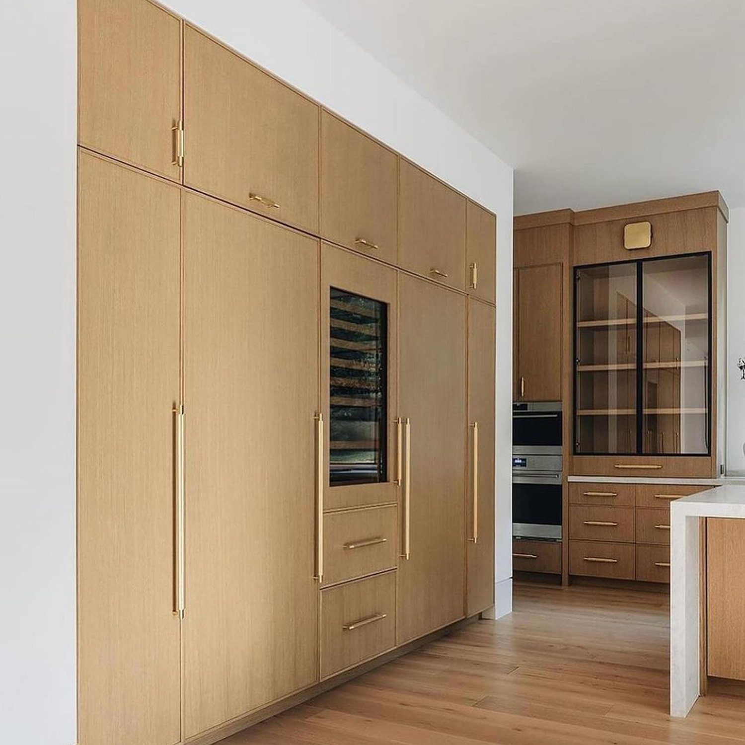 A sleek modern kitchen featuring wood-finished cabinetry and integrated appliances