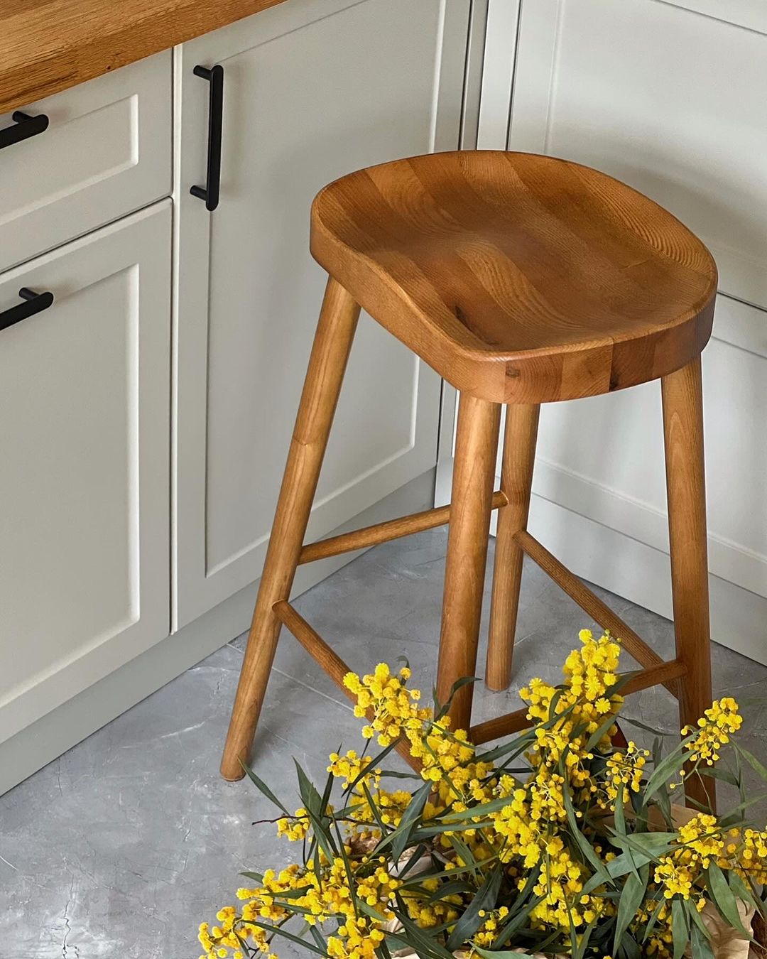 A modern wooden bar stool in a kitchen setting