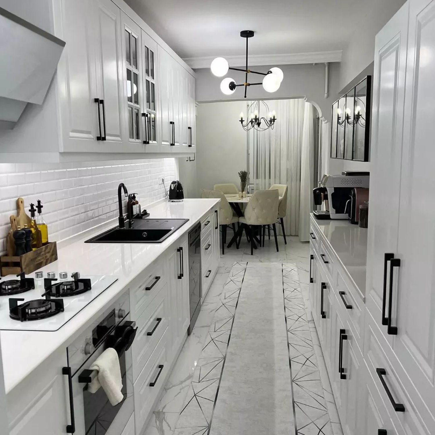 Elegant monochrome kitchen design with white cabinetry and modern lighting fixtures