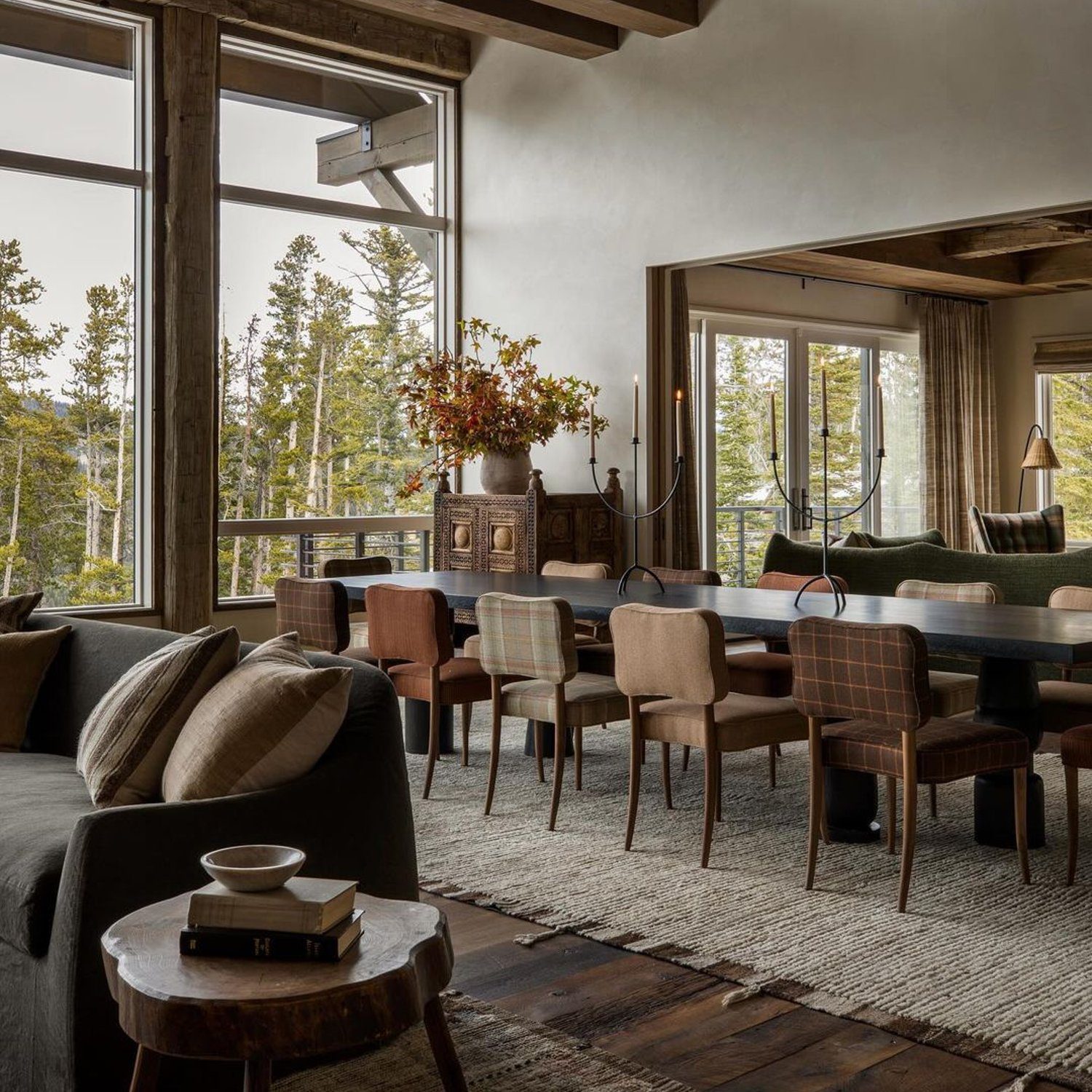 A cozy mountain retreat living room with large windows and a forest view.