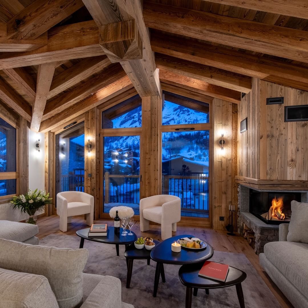 A cozy mountain retreat living room with a warm fireplace and snow views