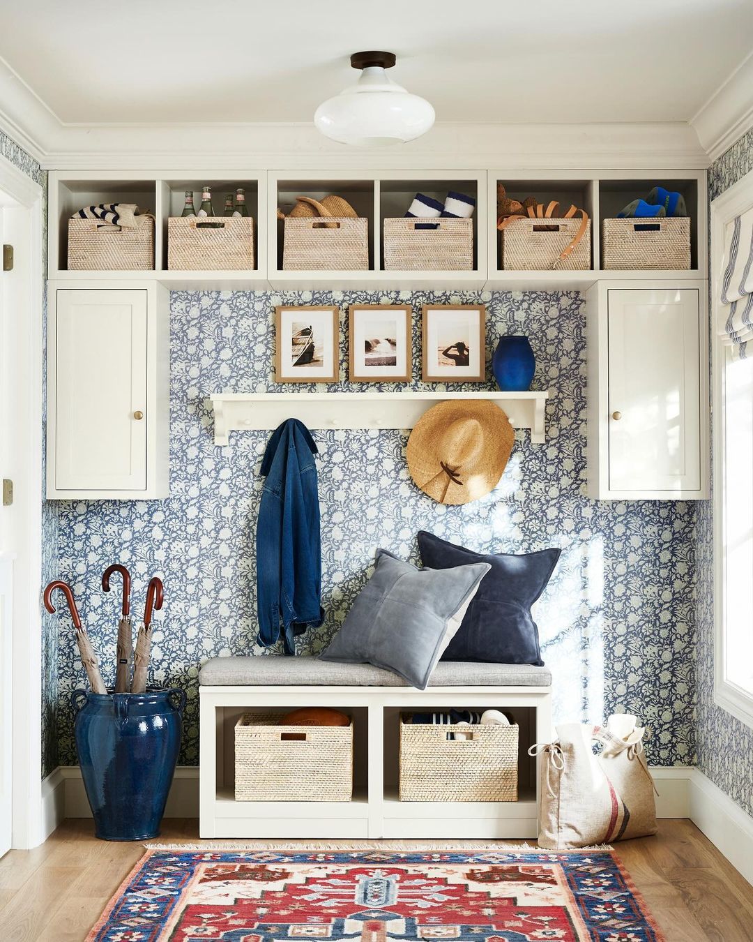 A well-organized mudroom featuring blue and white patterned wallpaper