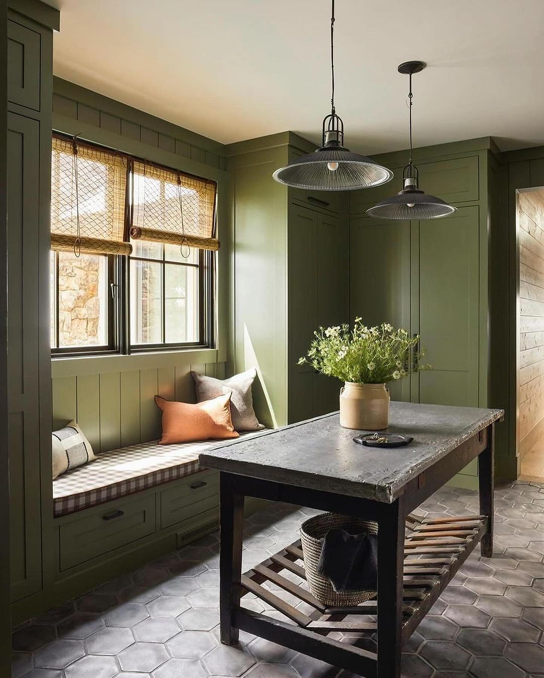 A harmoniously designed mudroom with sage green built-ins and checkered cushions