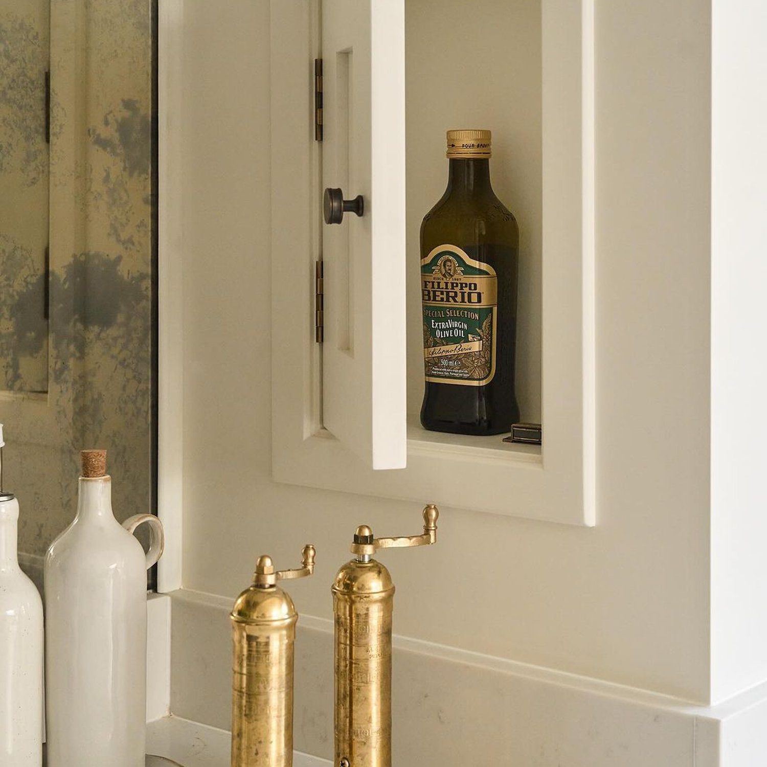 Filippo Berio Olive Oil displayed in a niche above a bathroom sink with brass fixtures