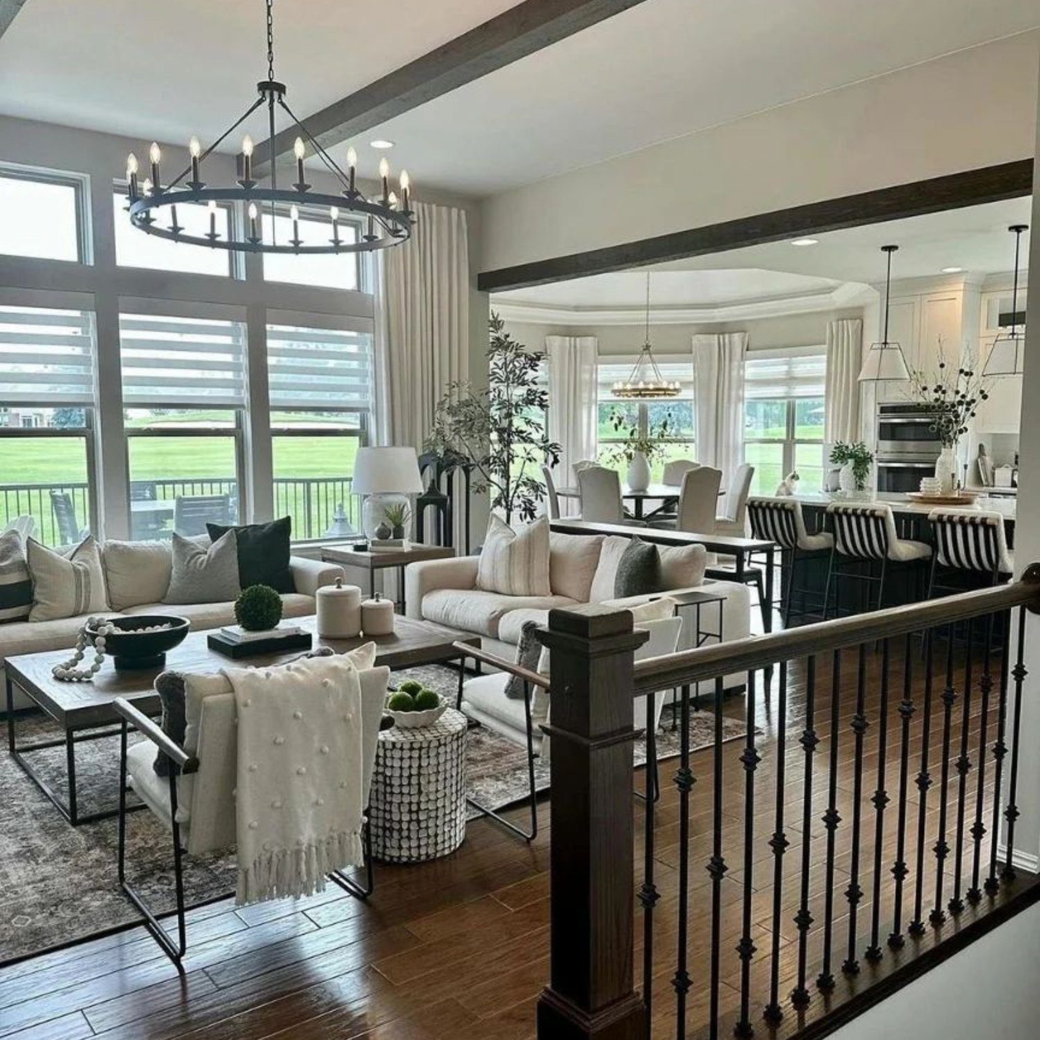 Elegant open-concept living space with hardwood floors and decorative ceiling beams