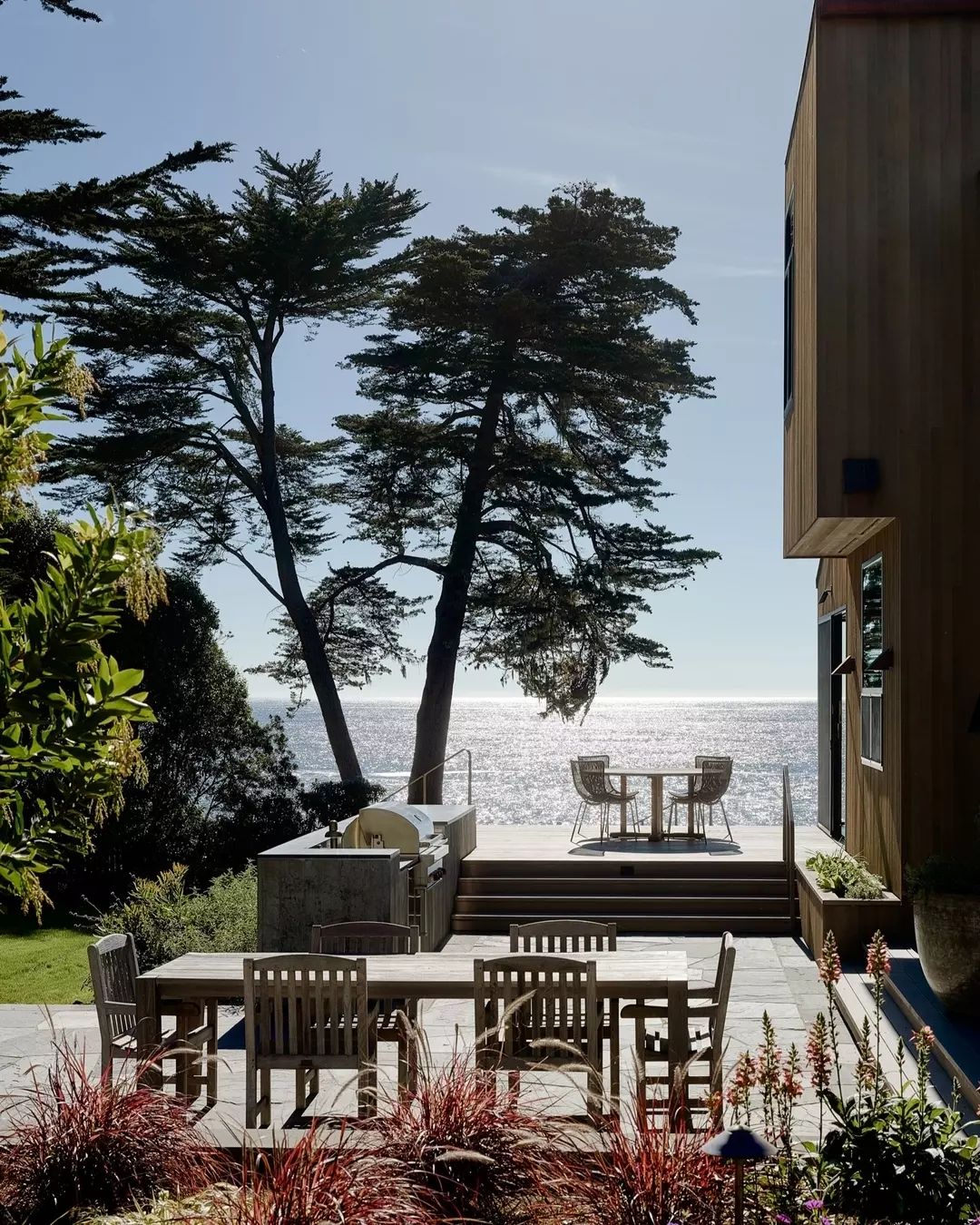 A serene outdoor patio setting with towering trees and ocean view