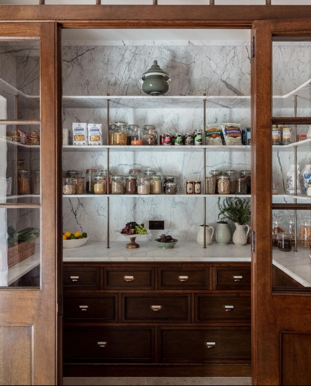 A pantry with wooden cabinetry and marble backdrop