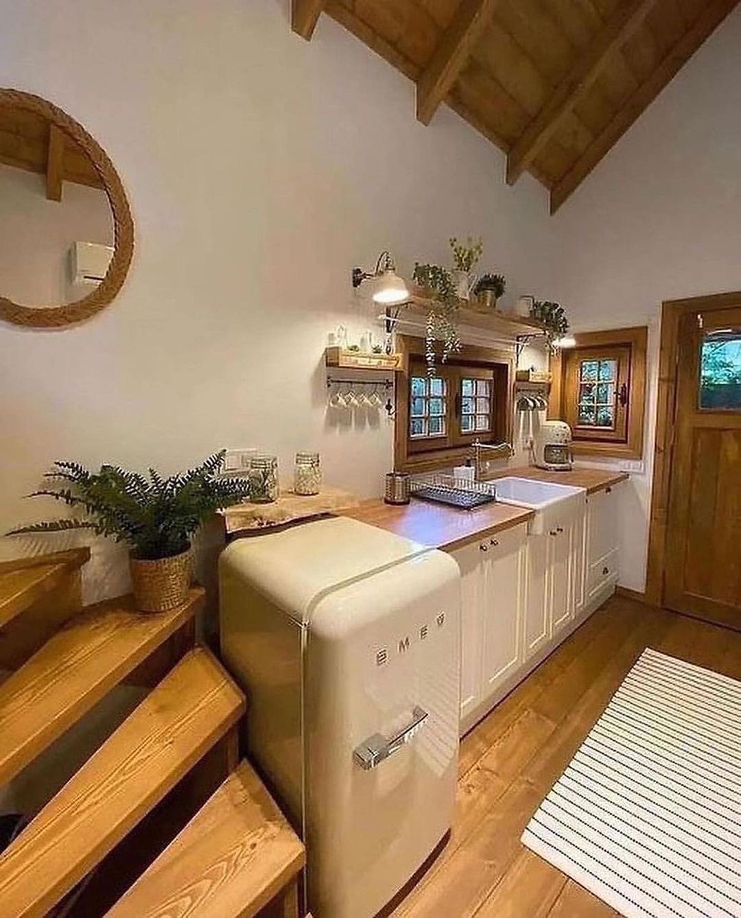 A rustic kitchen featuring warm wooden accents, a retro-style cream fridge, and classic white cabinetry.