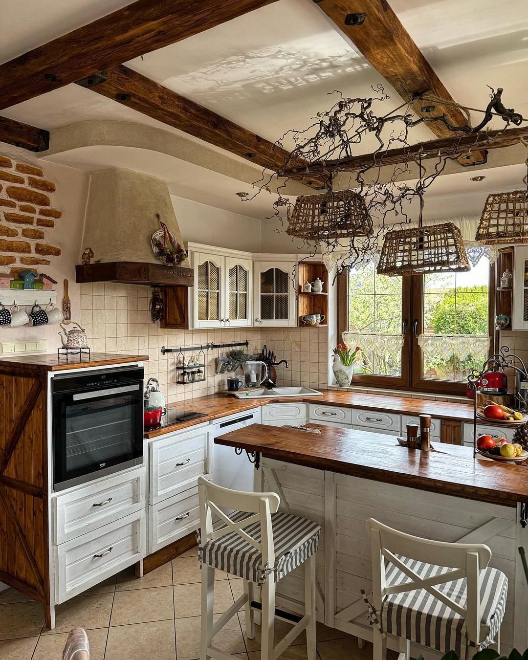 A cozy and rustic kitchen design with exposed wooden beams and a mix of white cabinetry and natural wood countertops.