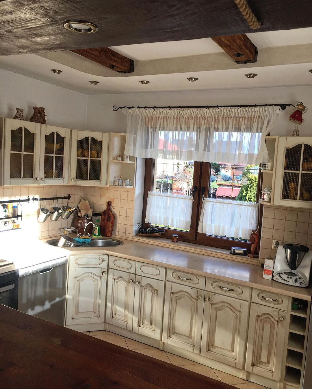 A rustic kitchen with exposed wooden beams and white cabinetry