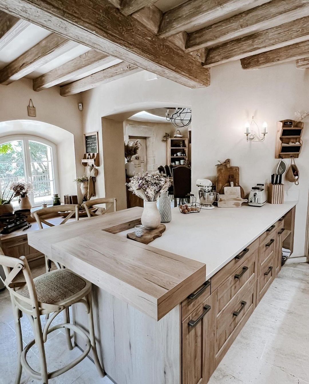 A rustic kitchen with charming character featuring exposed wooden beams and a central island.