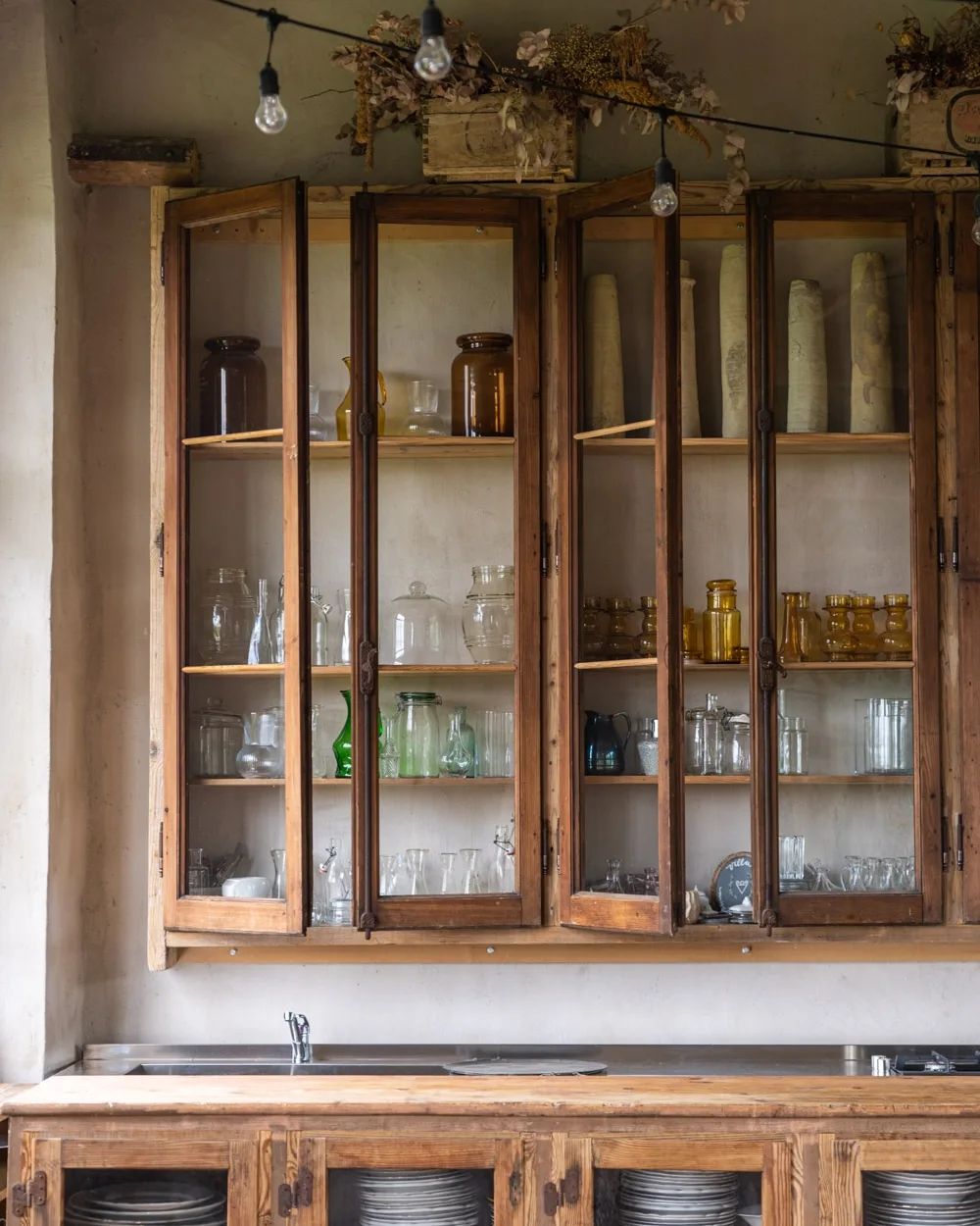 A rustic-style kitchen featuring glass-front wooden cabinetry and an undermount sink