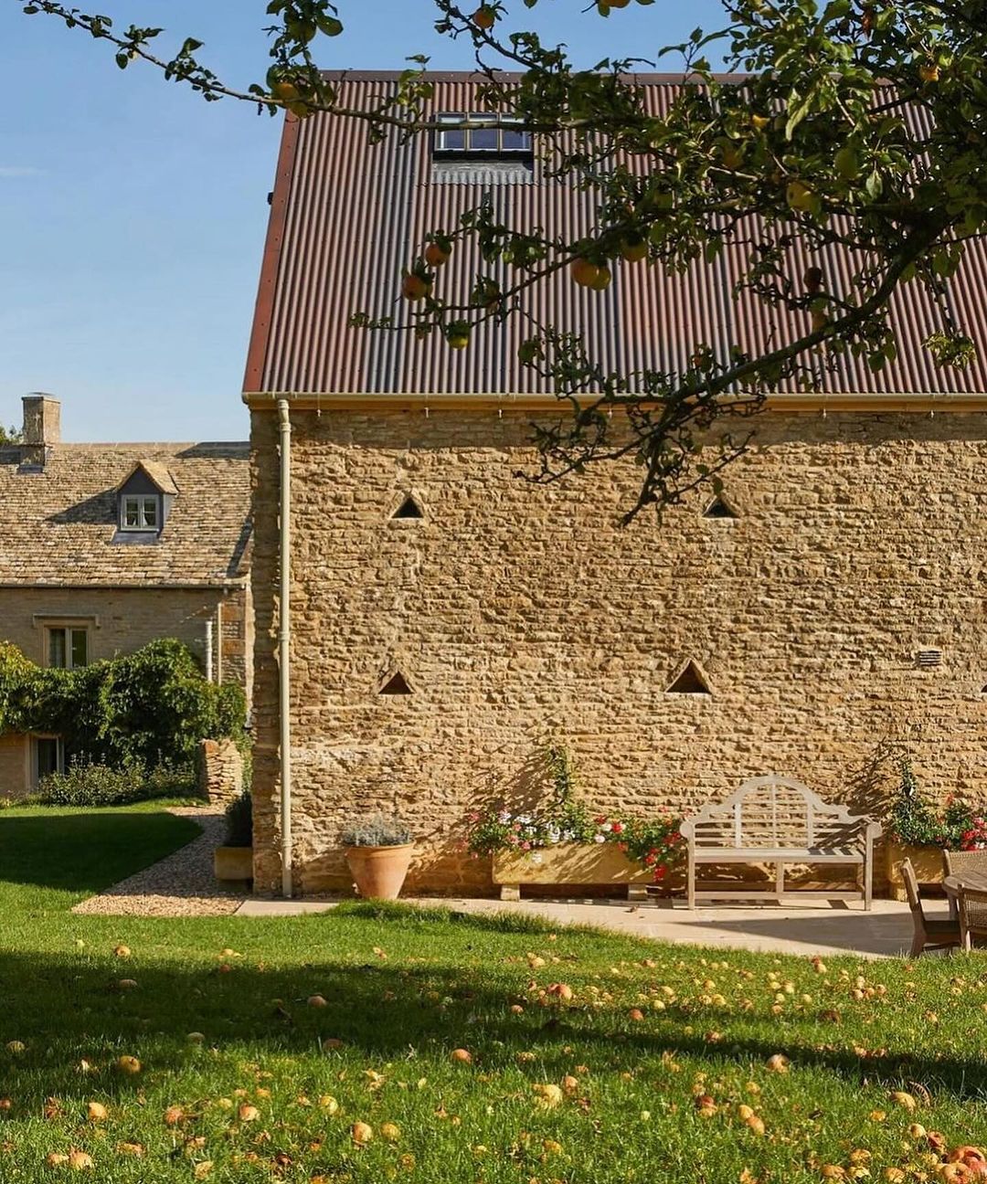 Traditional stone house with a terracotta roof and apple orchard