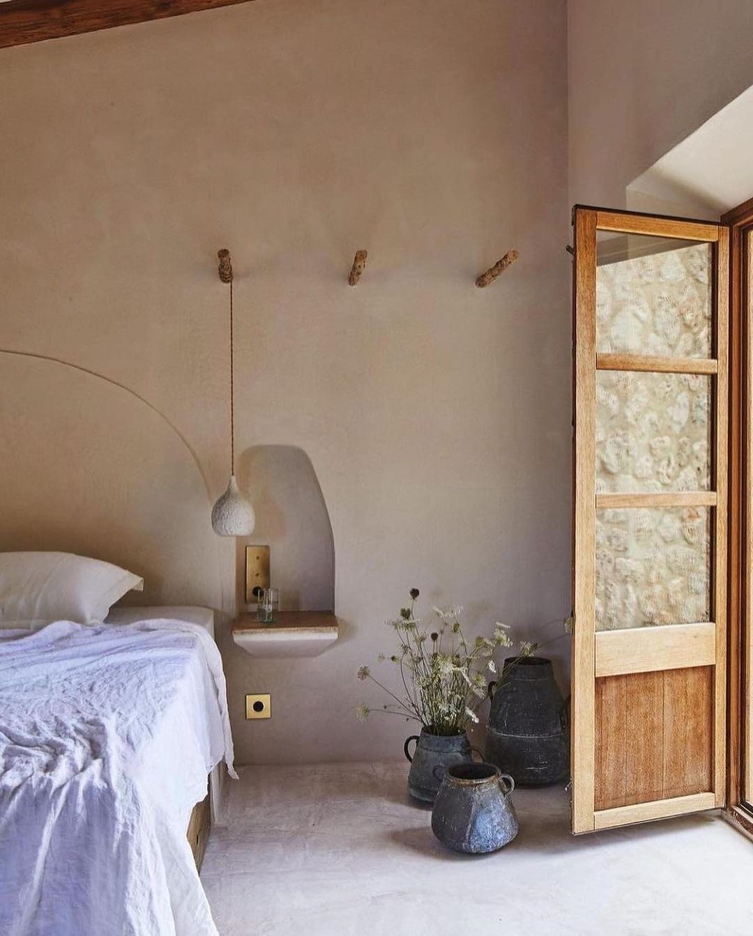 A serene bedroom with minimalist design featuring an arched alcove and earthy tones