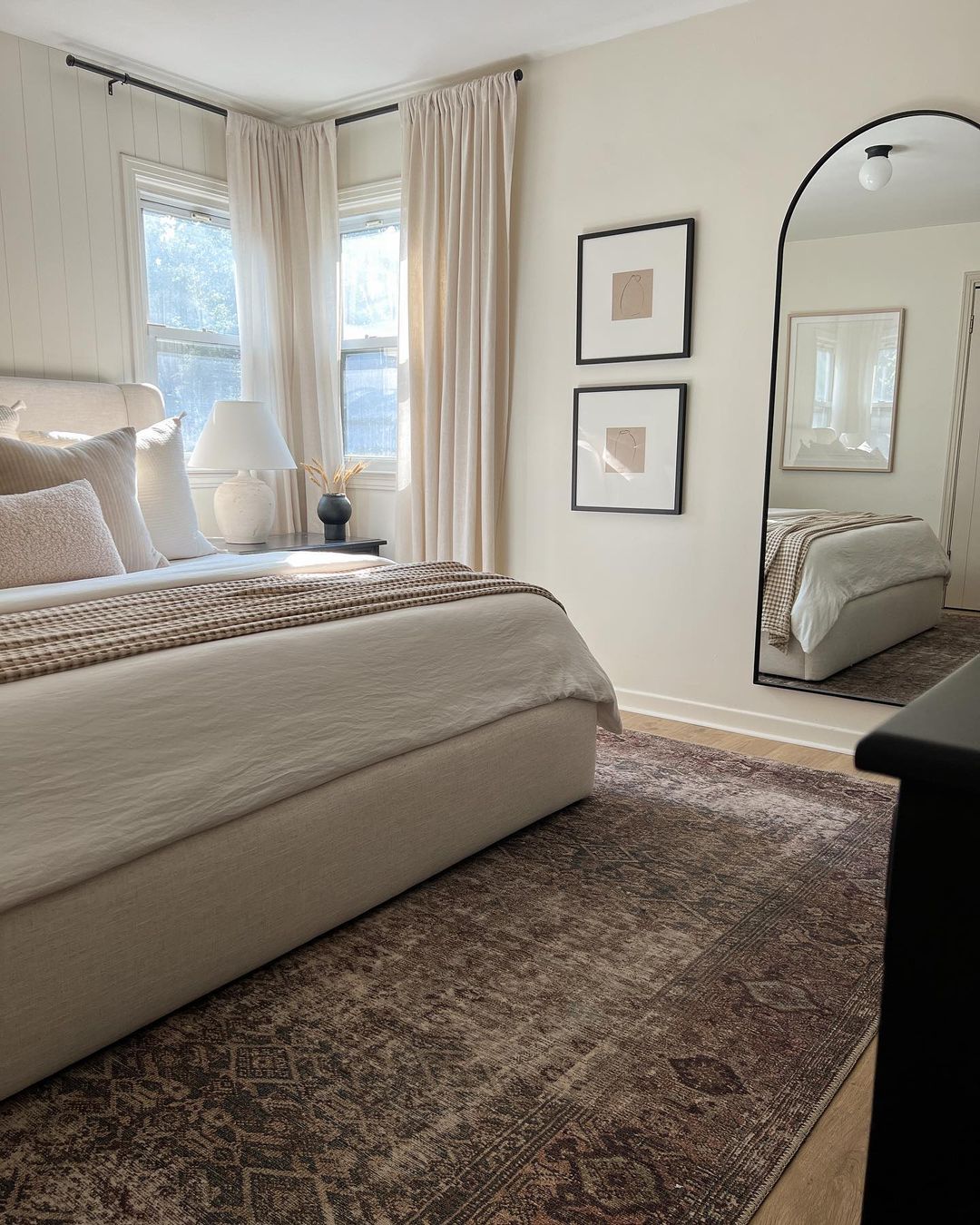 A serene bedroom featuring a classic window with soft curtain drapery