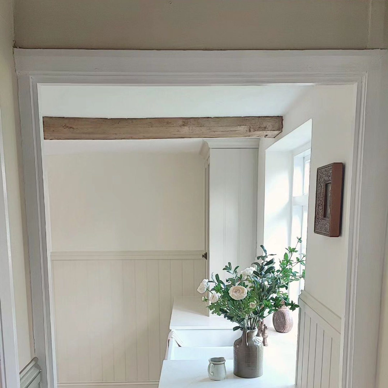 A serene entryway featuring exposed wooden beams and a calming neutral color palette