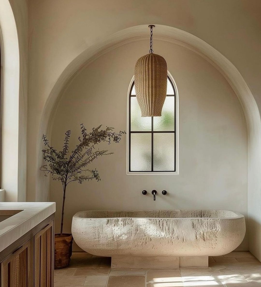 A serene and minimalist bathroom design featuring arched ceilings and a textured freestanding bathtub