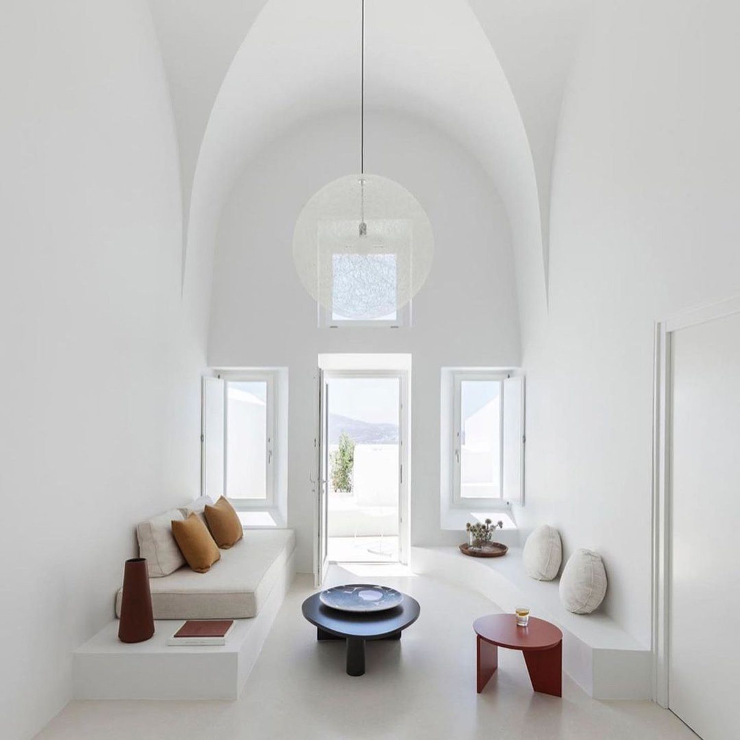 A spacious and minimalist interior design featuring arched ceilings and natural light