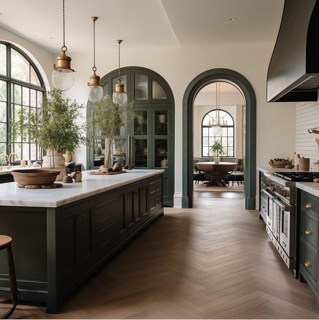 A sophisticated kitchen design featuring arched windows and dark green cabinetry.