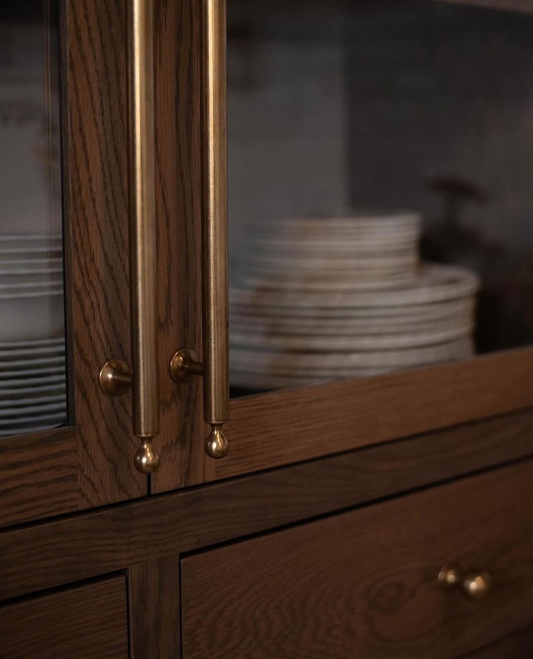 Close up of a dark wooden cabinet with brass knobs and handles