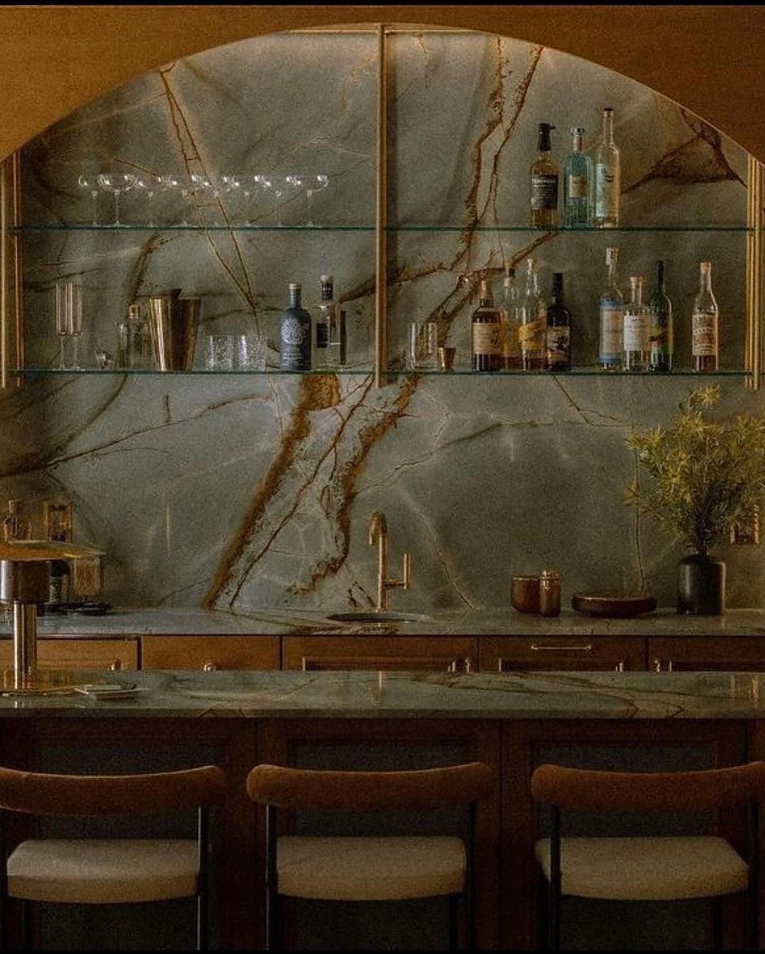 A sophisticated home bar with dark wood cabinetry and striking marble backsplash