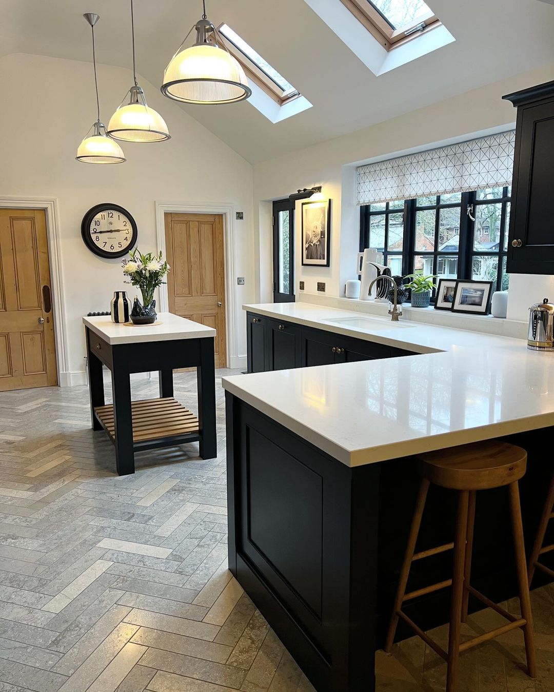 A sophisticated kitchen featuring herringbone-patterned flooring and black cabinetry