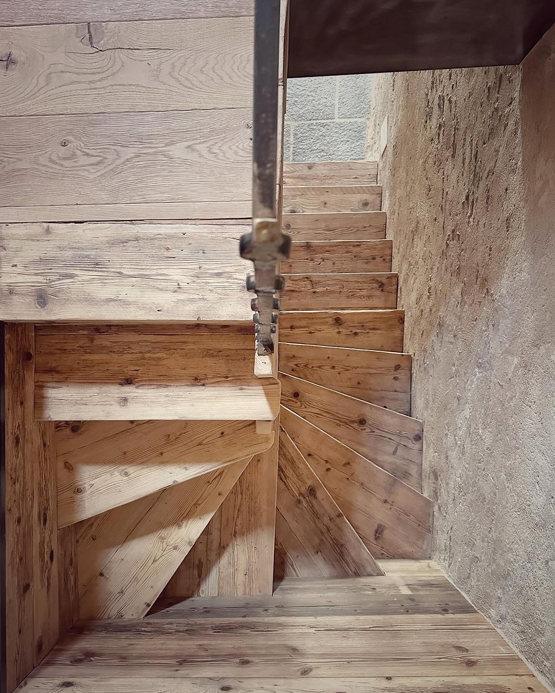 A rustic wooden staircase framed by rough concrete walls