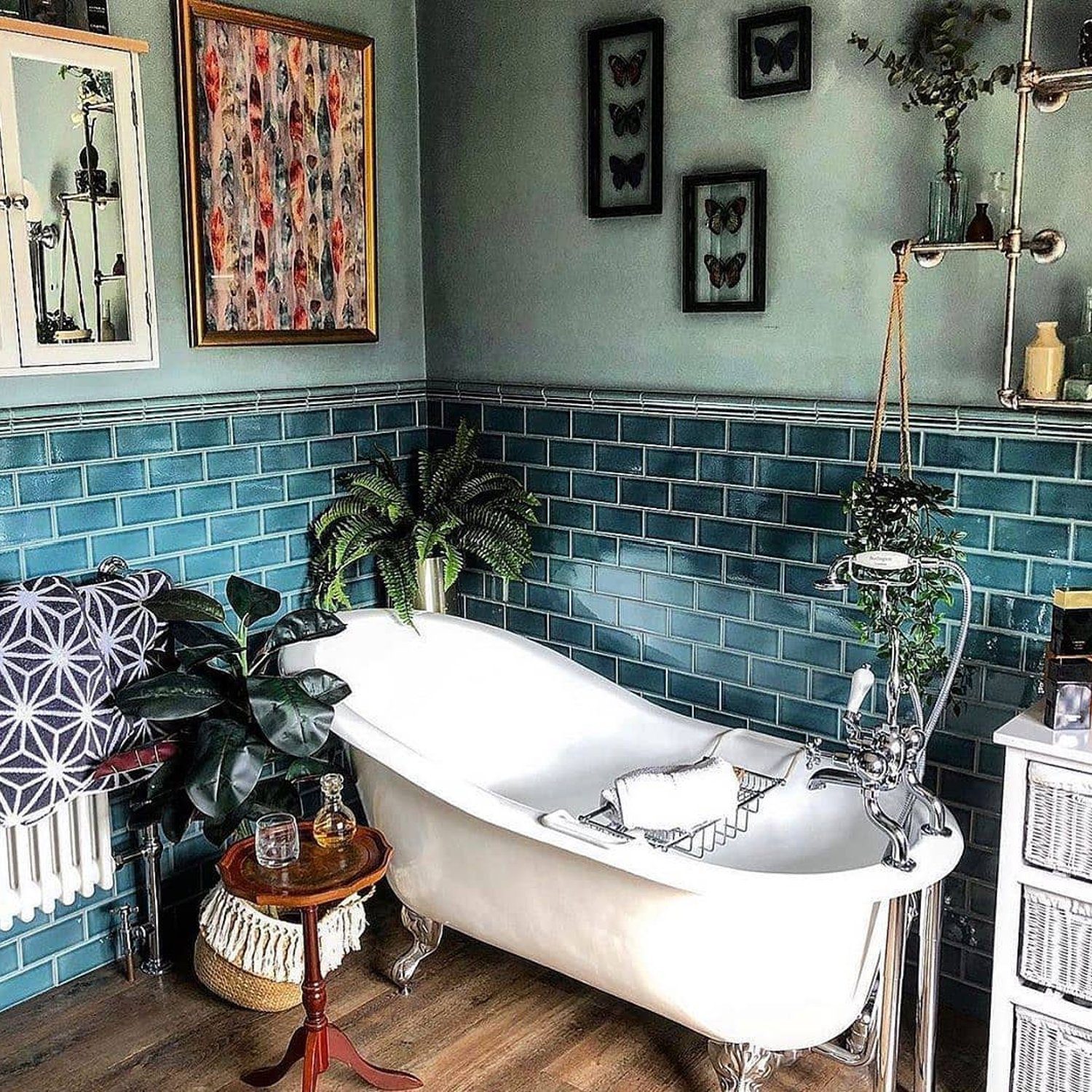 A stylish bathroom featuring a classic claw-foot tub amidst teal subway tiles