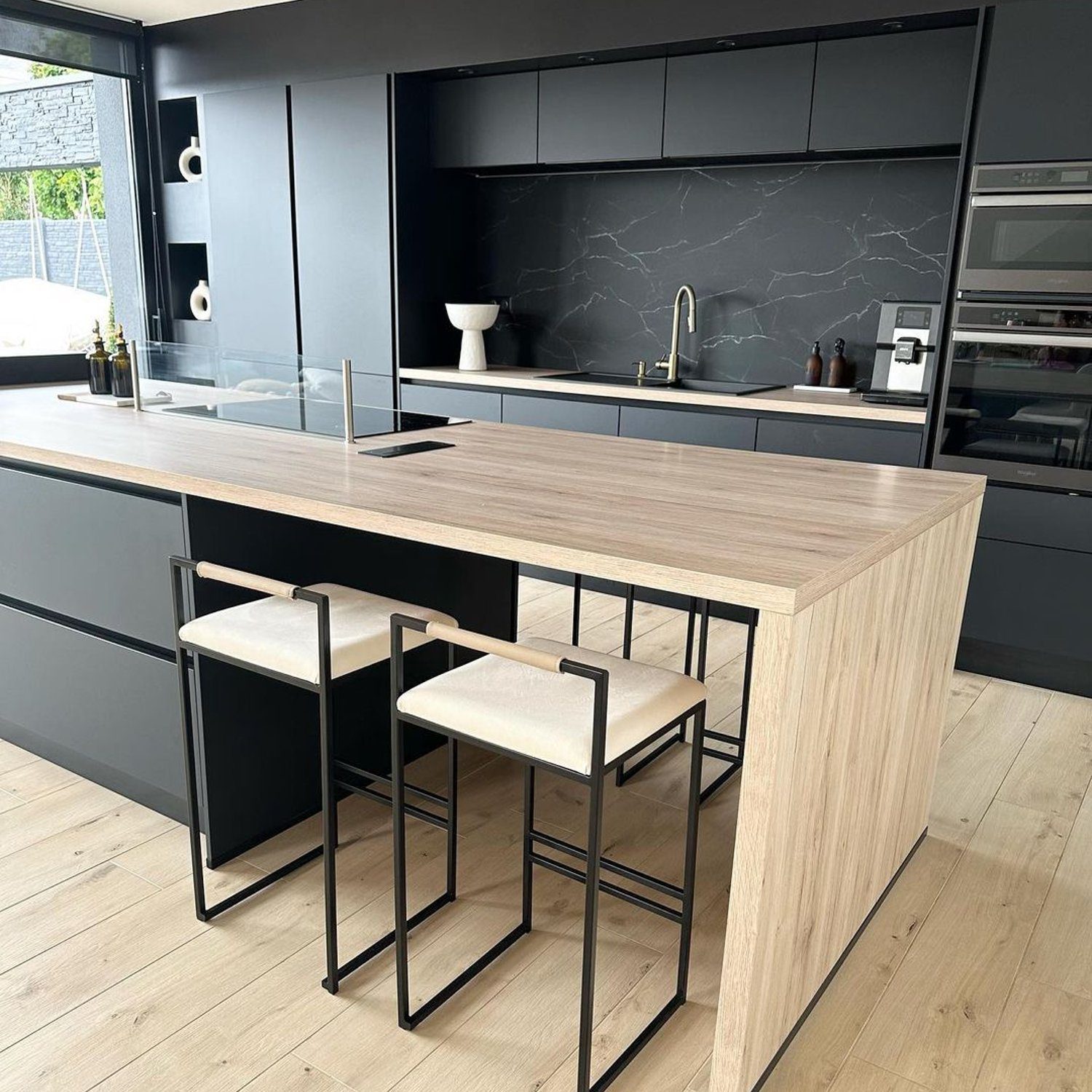 A modern kitchen featuring dark cabinetry and marble backsplash