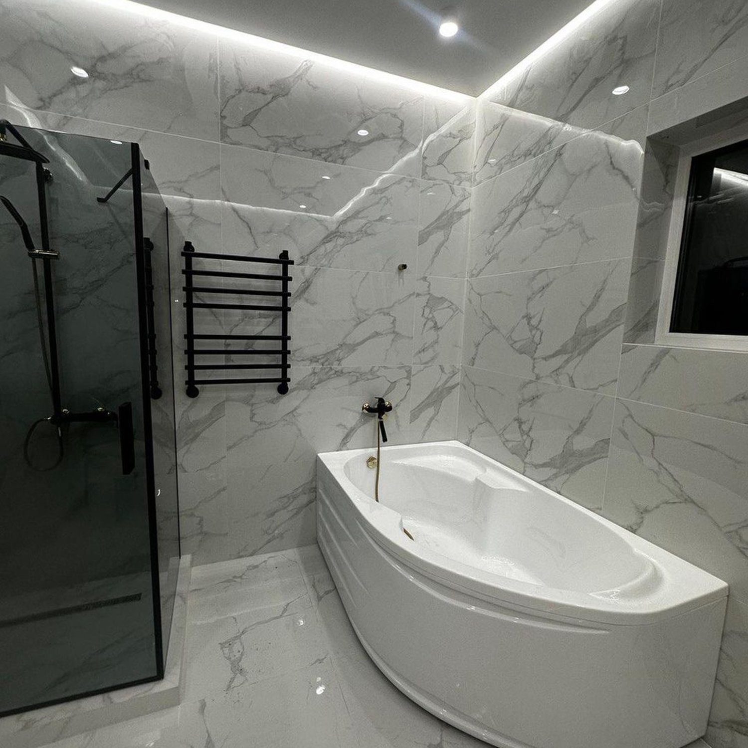 Modern marble tiled bathroom with a sleek free-standing tub and a glass shower cabin