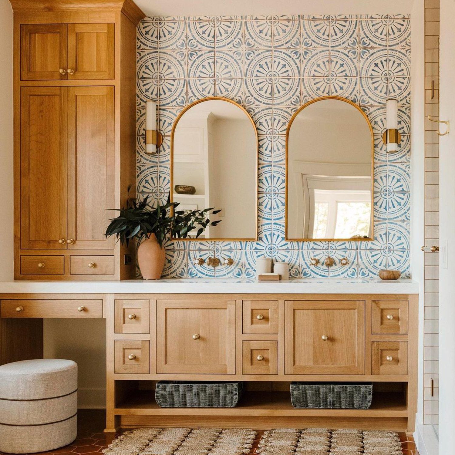 Elegant bathroom featuring terracotta hexagon floor tiles, natural wood cabinetry, and intricate blue geometric wallpaper.