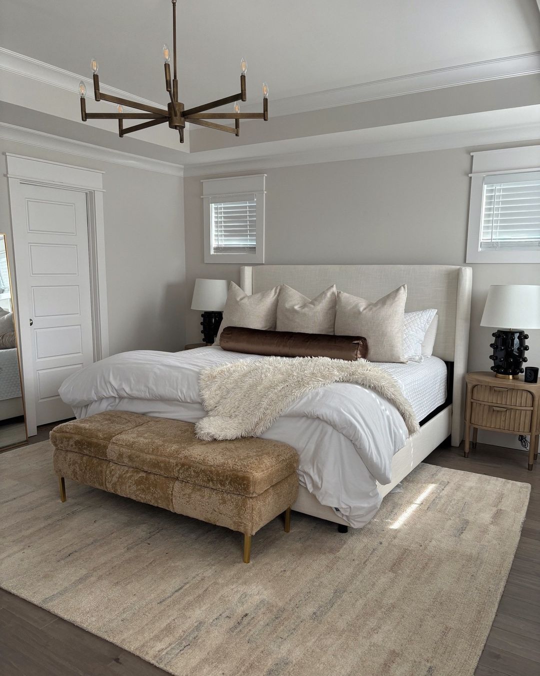 A serene and stylish bedroom with a chic chandelier and plush bench