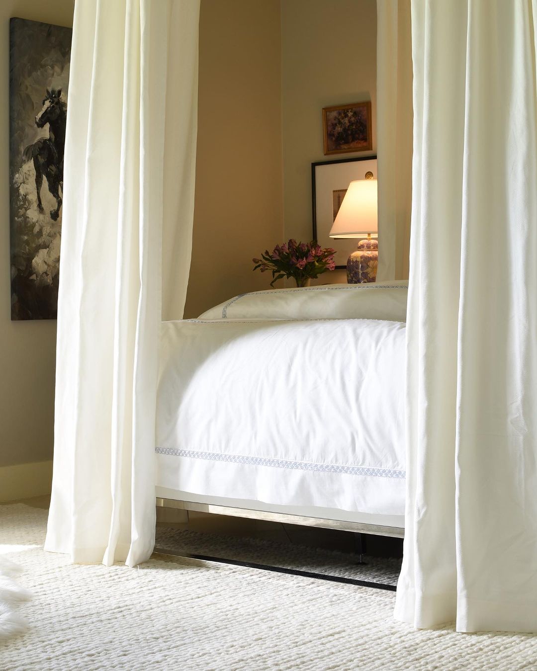 A cozy and inviting bedroom featuring a lavish canopy bed with pristine white linens.